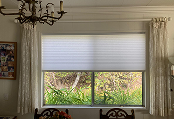 Cellular shades combined with sheer curtains on small dining room window